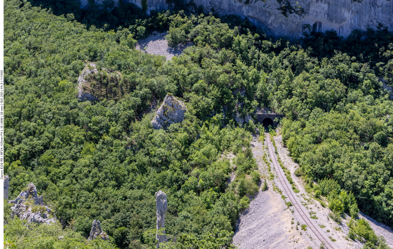 Einsame Kalksteinsäule und Eisenbahnstrecke im Tal