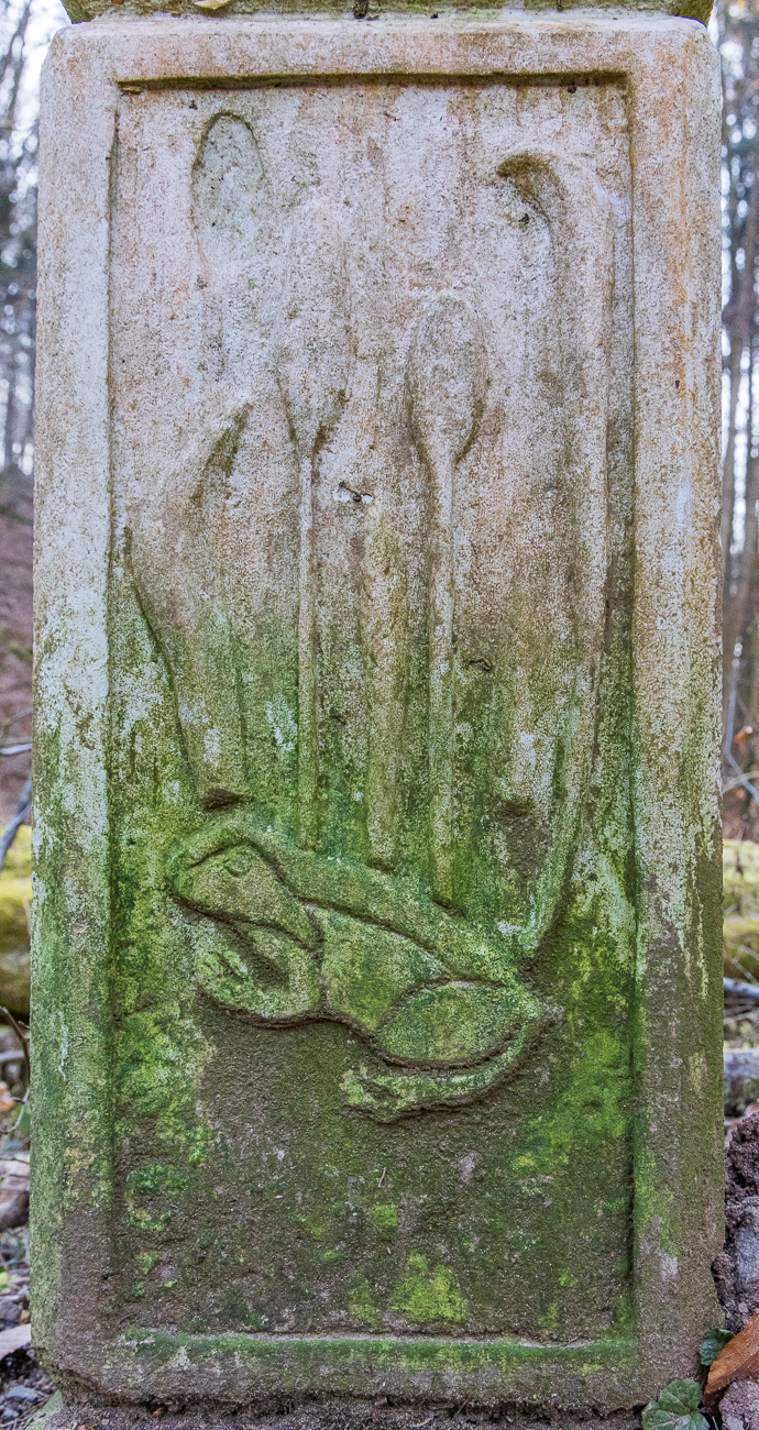 Frosch und Wasserpflanzen als Steinbildhauerei unter dem Infoschild